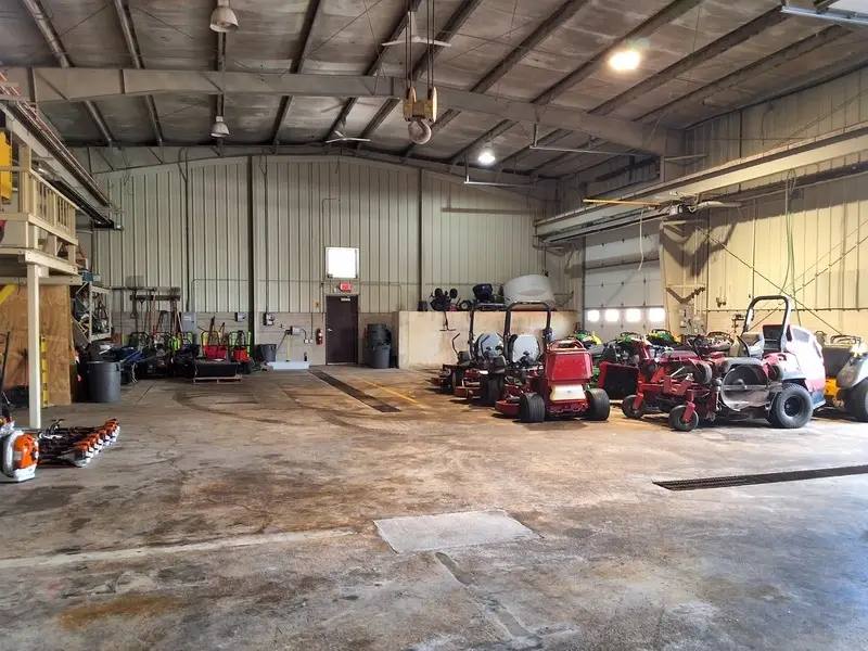 Inside a high-bay service shop with landscaping equipment